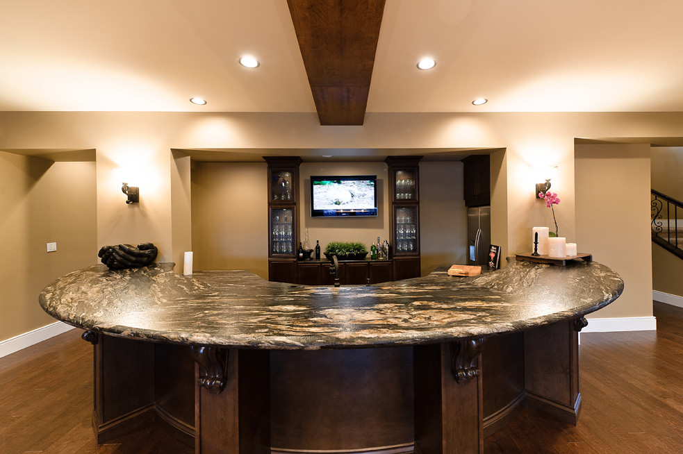 Photo of a small arts and crafts u-shaped seated home bar in Edmonton with glass-front cabinets, dark wood cabinets, granite benchtops and dark hardwood floors.