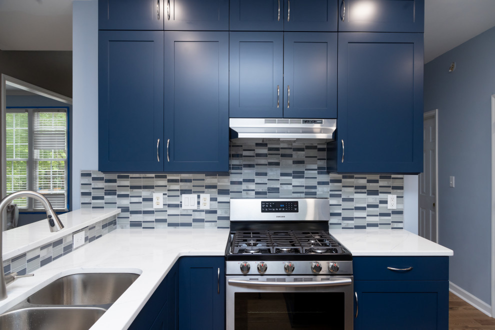 Foto di una grande cucina minimal con ante in stile shaker, ante blu, top in quarzo composito, paraspruzzi con piastrelle di vetro e top bianco