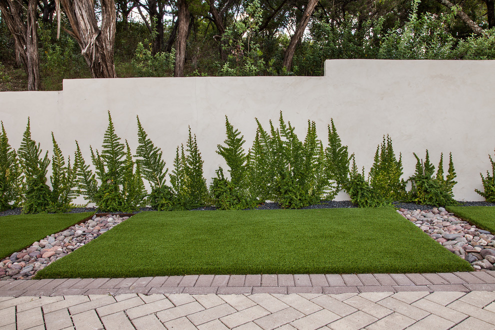 Photo of a large modern sloped full sun xeriscape for spring in Austin with natural stone pavers and a garden path.