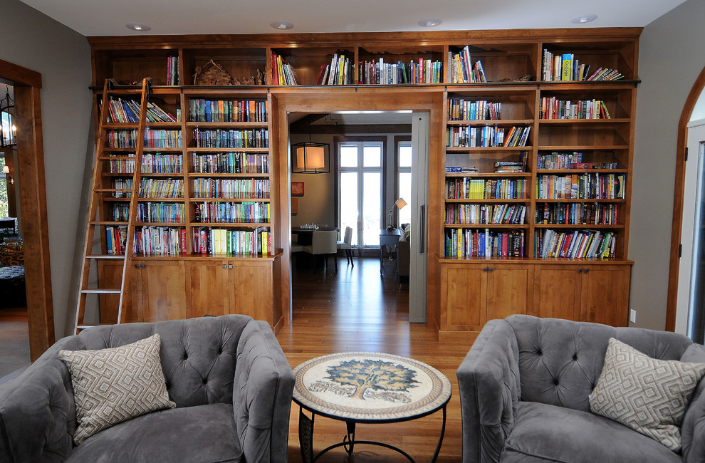 This is an example of a traditional living room in Other with a library and light hardwood floors.