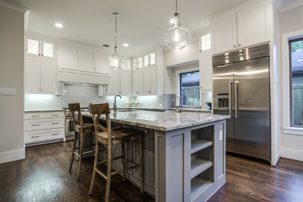 This is an example of a large transitional u-shaped eat-in kitchen in Dallas with a farmhouse sink, shaker cabinets, white cabinets, granite benchtops, blue splashback, subway tile splashback, stainless steel appliances, dark hardwood floors and with island.
