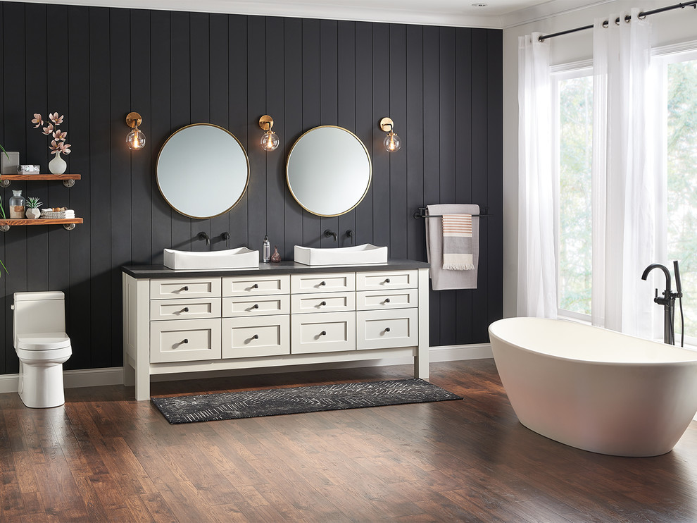 This is an example of an expansive country master bathroom in Indianapolis with shaker cabinets, beige cabinets, a freestanding tub, a one-piece toilet, black walls, a vessel sink, engineered quartz benchtops, brown floor and grey benchtops.