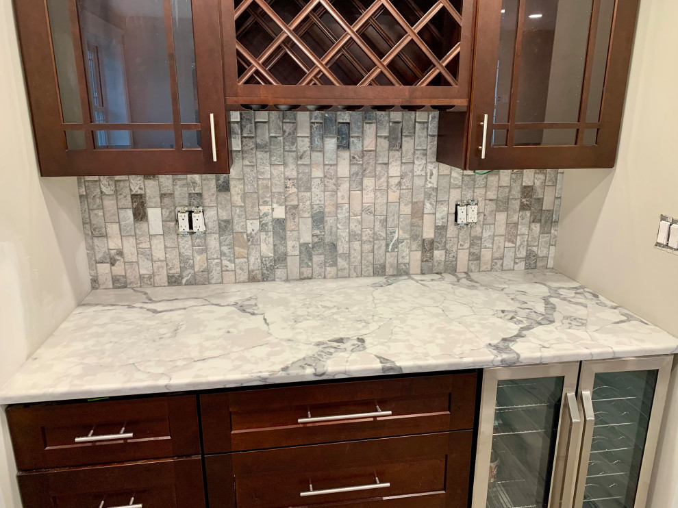 This is an example of a small traditional galley kitchen pantry in Chicago with glass-front cabinets, dark wood cabinets, quartz benchtops, grey splashback, granite splashback, stainless steel appliances, porcelain floors, beige floor and grey benchtop.