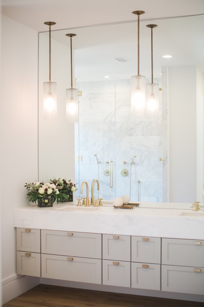 Inspiration for a mid-sized modern master bathroom in Orange County with shaker cabinets, grey cabinets, a japanese tub, a double shower, a one-piece toilet, white tile, marble, white walls, light hardwood floors, an undermount sink, marble benchtops, brown floor, a hinged shower door and white benchtops.