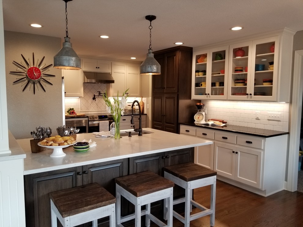Design ideas for a mid-sized country eat-in kitchen in Kansas City with white cabinets, quartz benchtops, white splashback, ceramic splashback, stainless steel appliances, dark hardwood floors, with island, brown floor and an undermount sink.