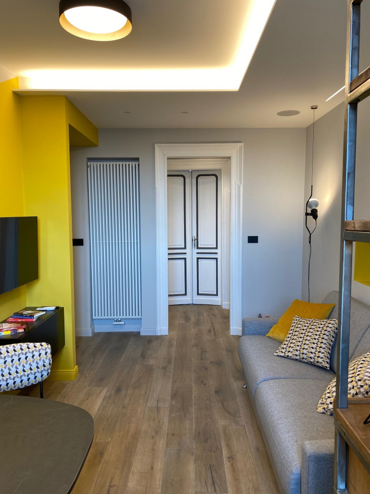 Kleines Industrial Foyer mit gelber Wandfarbe, dunklem Holzboden, Doppeltür, weißer Haustür, braunem Boden und eingelassener Decke in Turin