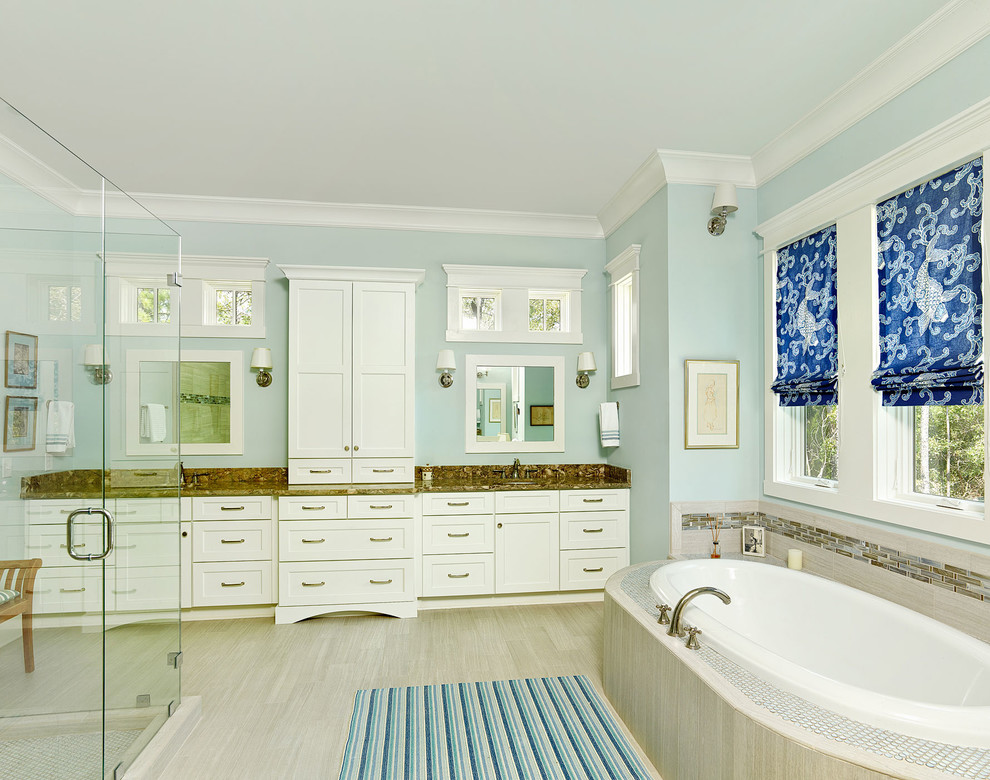Photo of a mid-sized beach style master bathroom in Charleston with a drop-in sink, recessed-panel cabinets, light wood cabinets, granite benchtops, a drop-in tub, an open shower, ceramic tile, porcelain floors, blue walls, beige floor, a hinged shower door and brown benchtops.