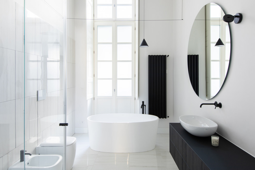 This is an example of a modern master bathroom in Turin with beaded inset cabinets, dark wood cabinets, an alcove tub, a curbless shower, a two-piece toilet, white tile, marble, white walls, marble floors, a vessel sink, engineered quartz benchtops, white floor, a hinged shower door and black benchtops.