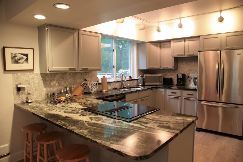 Small transitional u-shaped light wood floor kitchen photo in Indianapolis with a double-bowl sink, recessed-panel cabinets, beige cabinets, beige backsplash, mosaic tile backsplash, stainless steel appliances, a peninsula and granite countertops