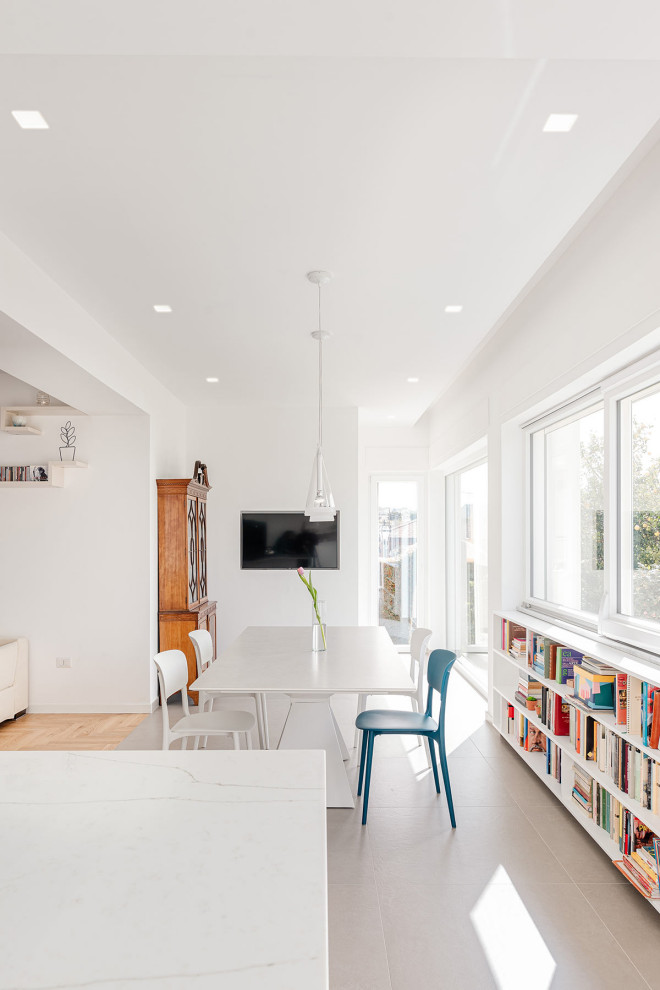 Foto di una sala da pranzo aperta verso il soggiorno minimal con pareti bianche, pavimento in gres porcellanato e pavimento beige