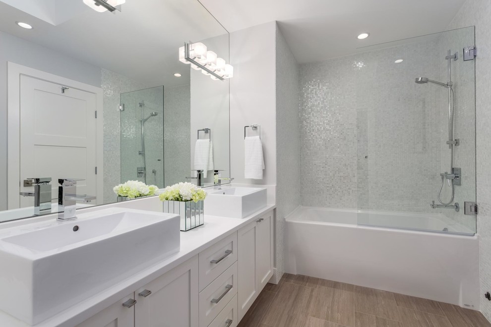 This is an example of a transitional bathroom in Vancouver with a vessel sink, shaker cabinets, white cabinets, an alcove tub, a shower/bathtub combo, white tile, mosaic tile and white walls.