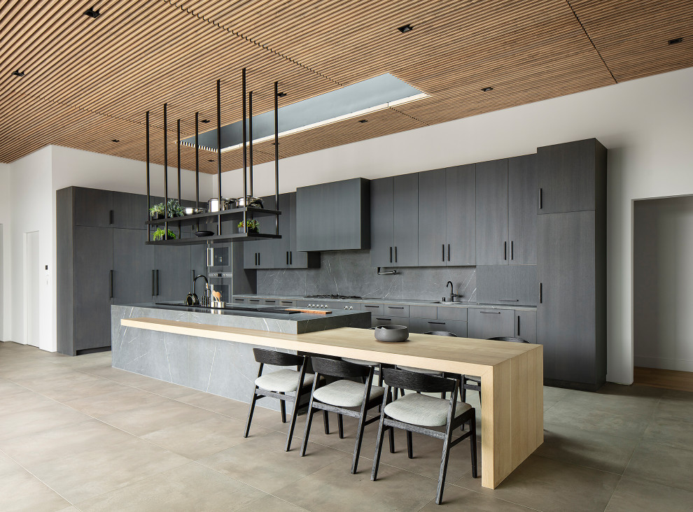 Huge l-shaped ceramic tile, gray floor and wood ceiling open concept kitchen photo in Los Angeles with a double-bowl sink, flat-panel cabinets, gray cabinets, marble countertops, gray backsplash, stone slab backsplash, stainless steel appliances, an island and gray countertops