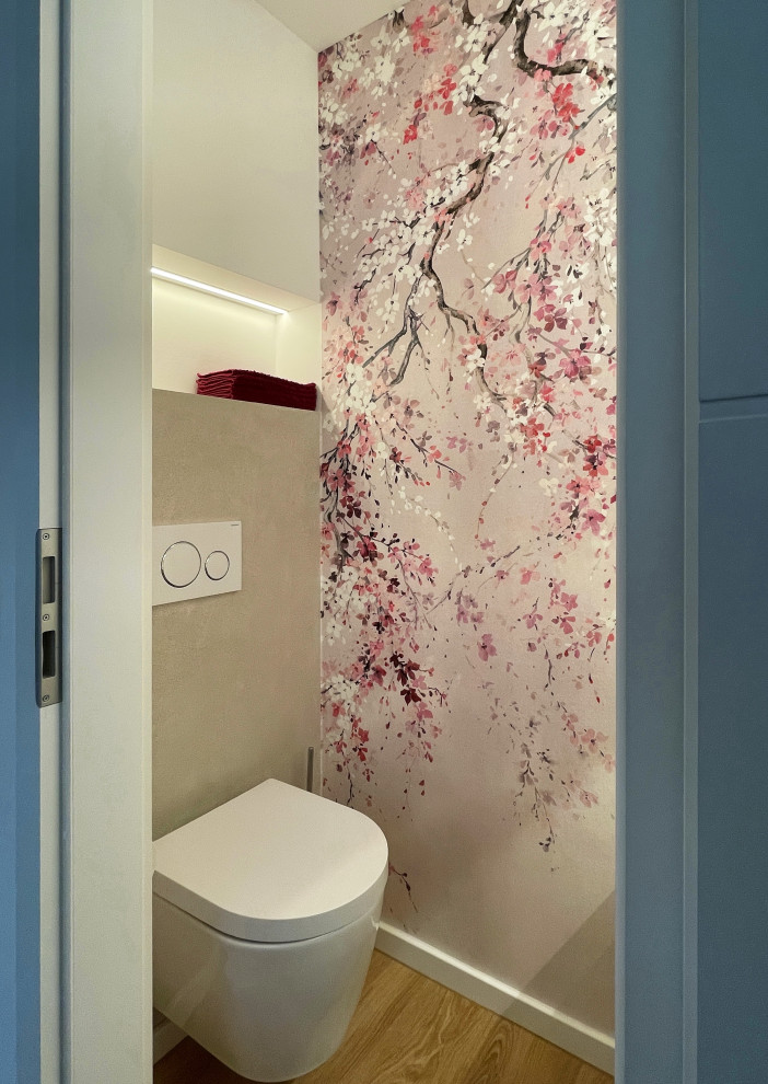 Cette image montre un petit WC suspendu design avec un carrelage beige, un mur beige, un sol en vinyl, une vasque, un sol marron, un plan de toilette beige, meuble-lavabo suspendu et du papier peint.