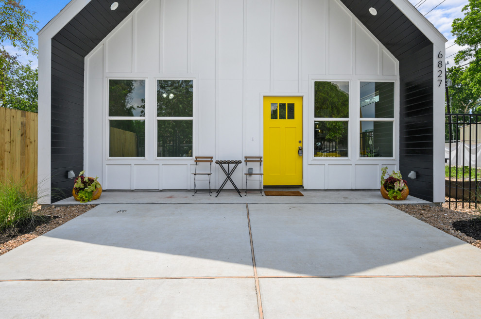 Bild på ett mellanstort funkis gult hus, med allt i ett plan, fiberplattor i betong, sadeltak och tak i shingel