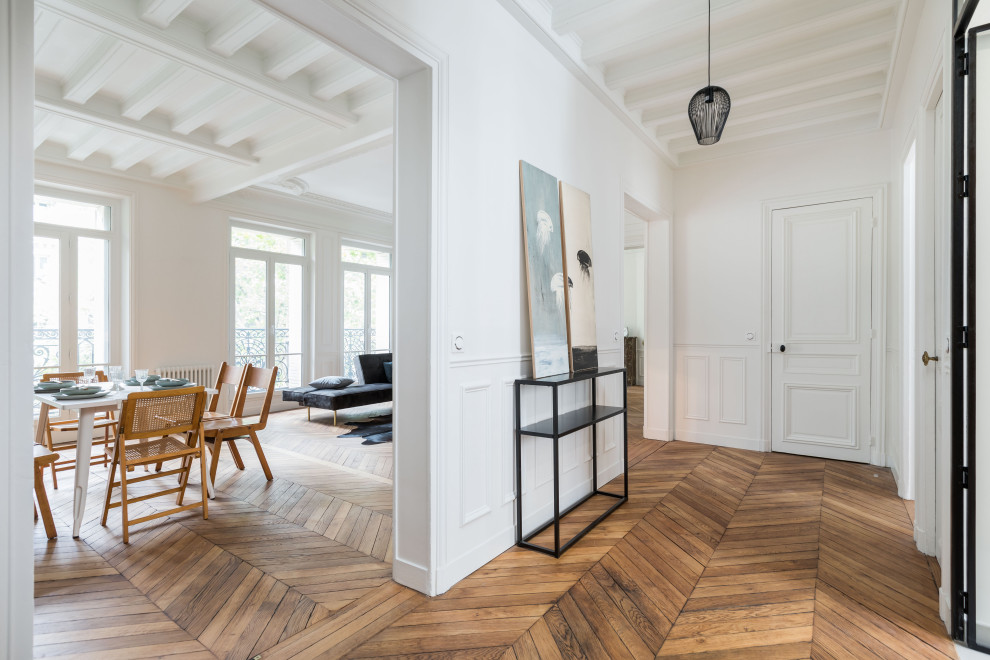 Photo of a large contemporary foyer in Paris with white walls, medium hardwood floors, a single front door, a white front door, brown floor, exposed beam and decorative wall panelling.