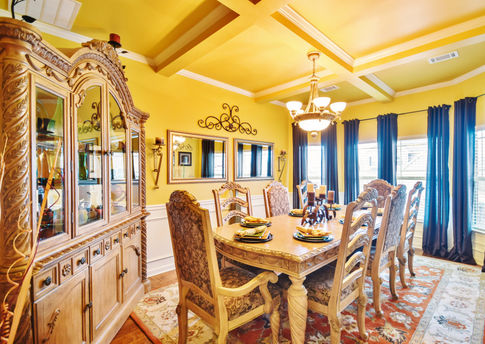 Elegant light wood floor, brown floor and coffered ceiling dining room photo in Other with yellow walls