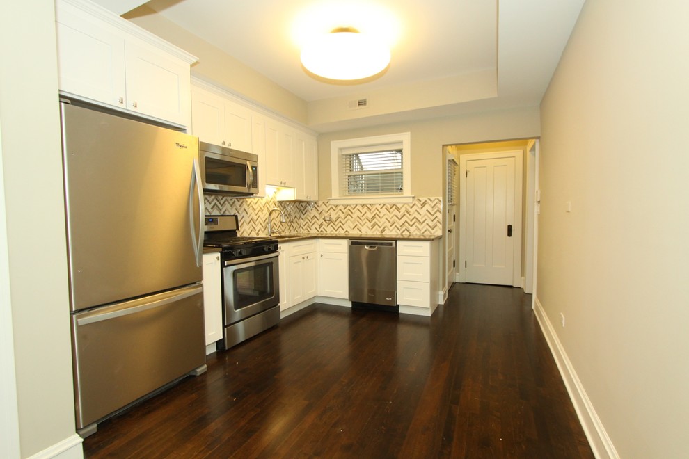 Mid-sized transitional l-shaped dark wood floor and brown floor enclosed kitchen photo in Chicago with an undermount sink, recessed-panel cabinets, white cabinets, quartz countertops, multicolored backsplash, ceramic backsplash, stainless steel appliances, no island and gray countertops