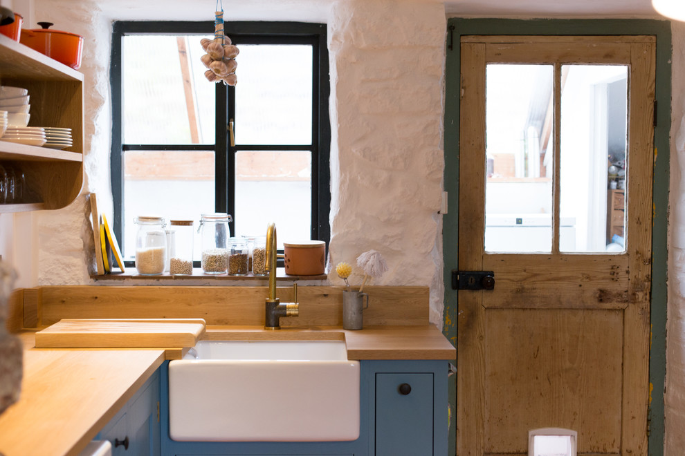 This is an example of a small contemporary galley separate kitchen in Other with a farmhouse sink, shaker cabinets, blue cabinets, wood benchtops, coloured appliances, with island, metallic splashback, metal splashback and terra-cotta floors.