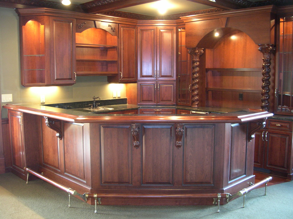 Photo of a mid-sized traditional l-shaped seated home bar in Cleveland with a drop-in sink, raised-panel cabinets, dark wood cabinets, wood benchtops, brown splashback, timber splashback and carpet.