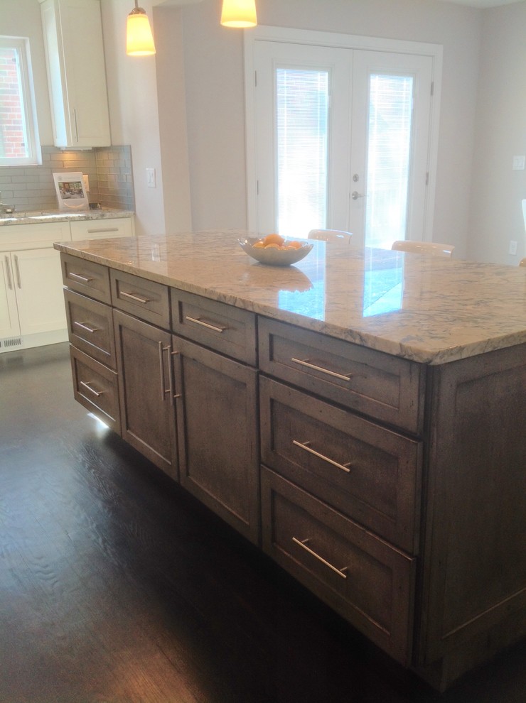 Eat-in kitchen - mid-sized transitional galley dark wood floor eat-in kitchen idea in Denver with a double-bowl sink, recessed-panel cabinets, white cabinets, granite countertops, gray backsplash, ceramic backsplash, stainless steel appliances and an island