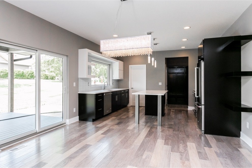 Example of a mid-sized minimalist galley light wood floor and gray floor eat-in kitchen design with a single-bowl sink, flat-panel cabinets, dark wood cabinets, quartzite countertops, white backsplash, glass tile backsplash, stainless steel appliances and an island