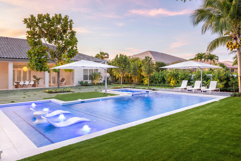 Large modern backyard custom-shaped lap pool in Miami with a hot tub.