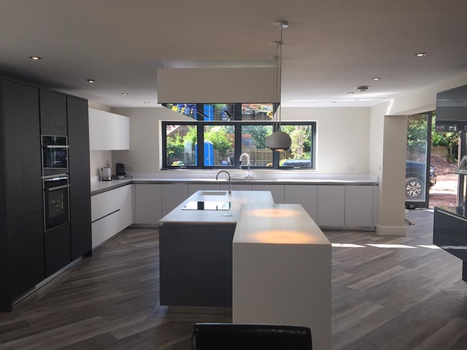 Inspiration for a large contemporary l-shaped eat-in kitchen in Other with an integrated sink, flat-panel cabinets, grey cabinets, solid surface benchtops, white splashback, panelled appliances, vinyl floors, with island and white benchtop.