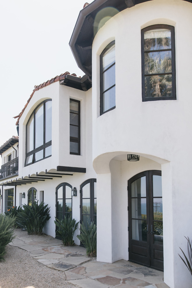 Mediterranean two-storey concrete white house exterior in Los Angeles with a gable roof and a tile roof.