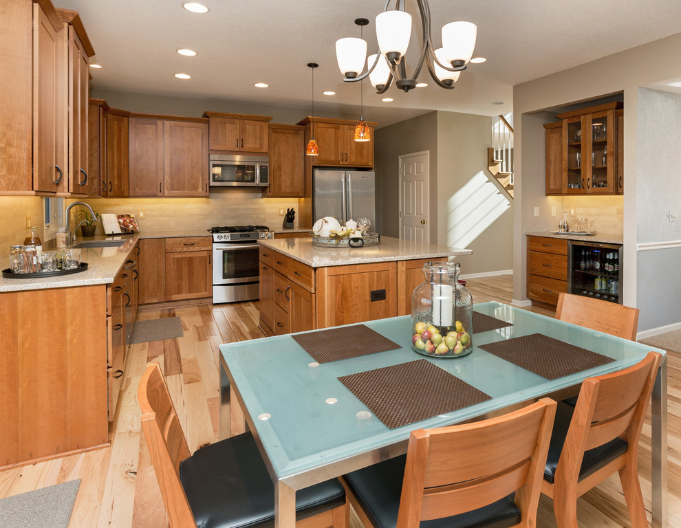 Open concept kitchen - mid-sized transitional l-shaped light wood floor open concept kitchen idea with an undermount sink, recessed-panel cabinets, medium tone wood cabinets, quartz countertops, beige backsplash, stone tile backsplash, stainless steel appliances and an island