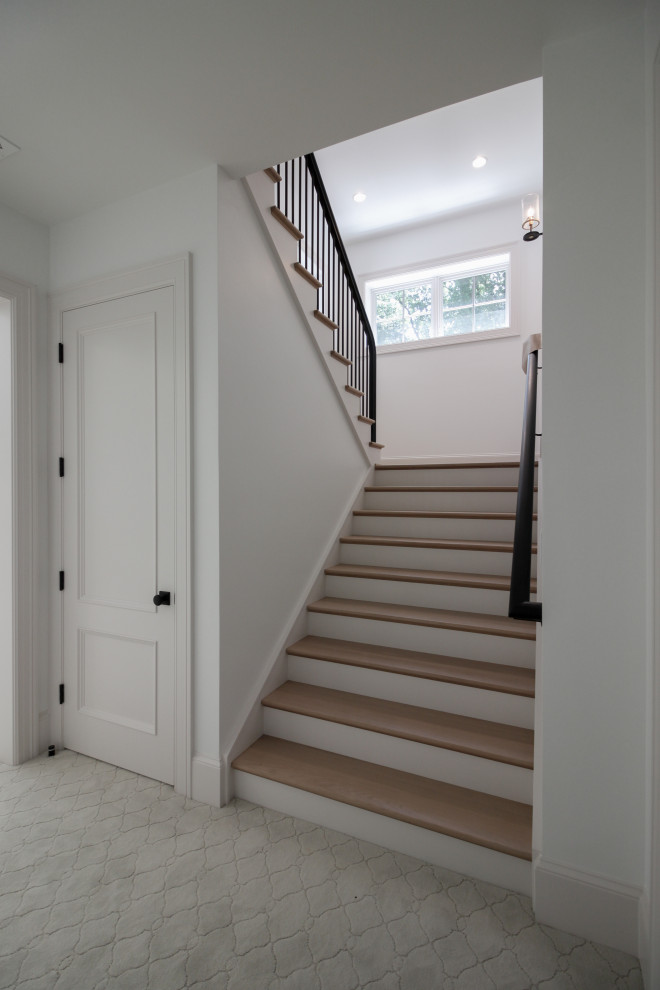 Imagen de escalera en U minimalista grande con escalones de madera, contrahuellas de madera pintada, barandilla de varios materiales y boiserie