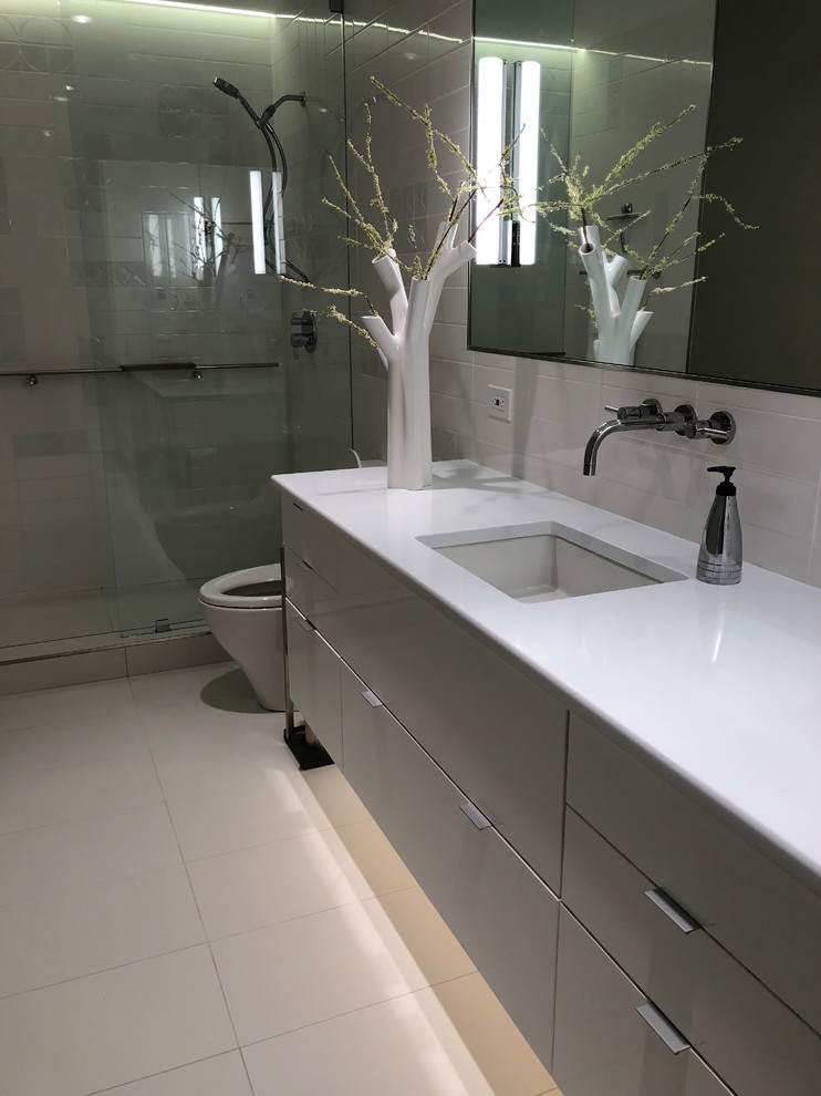 Inspiration for a small modern master bathroom in Dallas with glass-front cabinets, grey cabinets, an open shower, a one-piece toilet, white tile, ceramic tile, grey walls, porcelain floors, an undermount sink, engineered quartz benchtops, white floor, an open shower and white benchtops.