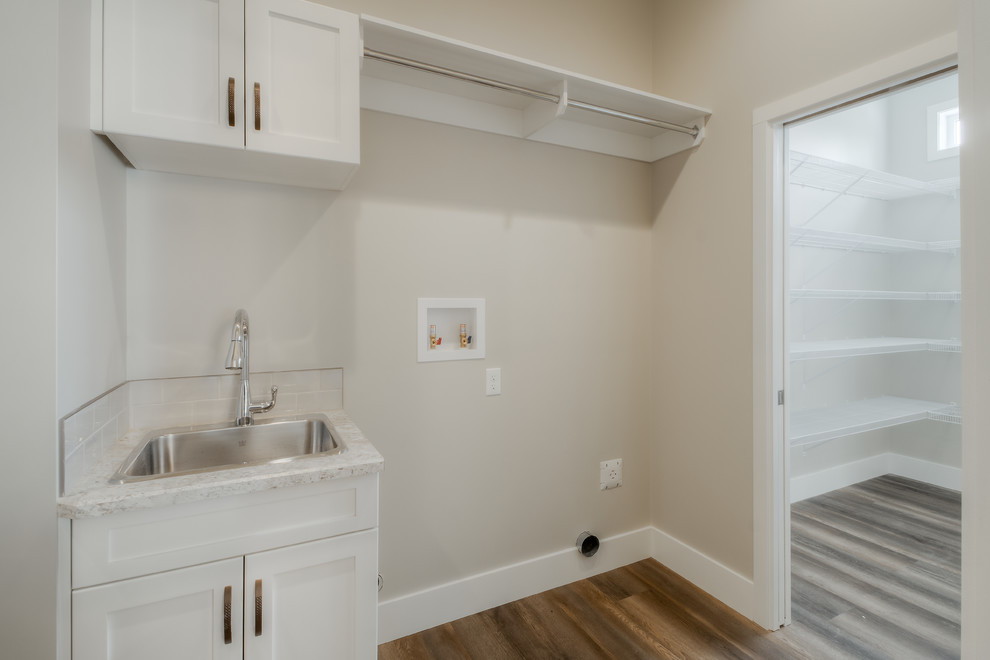 Mid-sized arts and crafts single-wall utility room in Calgary with a drop-in sink, shaker cabinets, white cabinets, laminate benchtops, beige walls, medium hardwood floors, a side-by-side washer and dryer, brown floor and white benchtop.