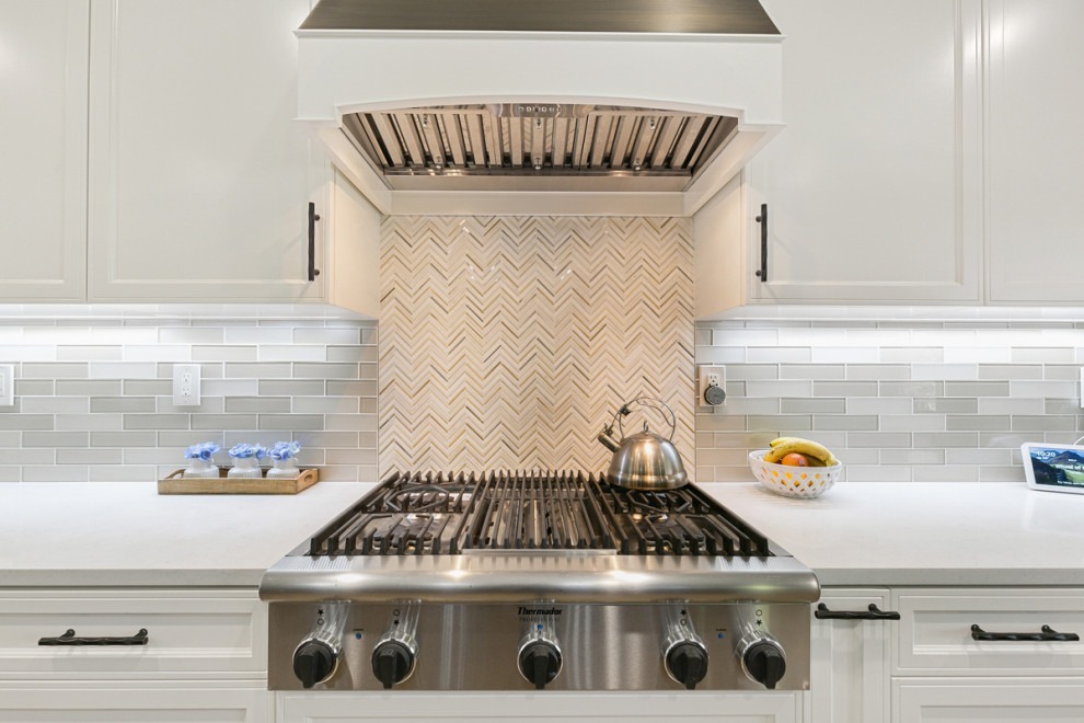 Huge transitional u-shaped travertine floor and beige floor open concept kitchen photo in Orange County with a single-bowl sink, shaker cabinets, white cabinets, quartz countertops, multicolored backsplash, stone tile backsplash, stainless steel appliances, an island and white countertops