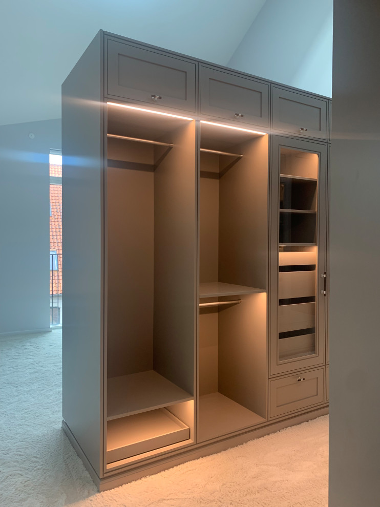 Design ideas for a medium sized scandinavian gender neutral walk-in wardrobe in Copenhagen with glass-front cabinets, grey cabinets, carpet and white floors.