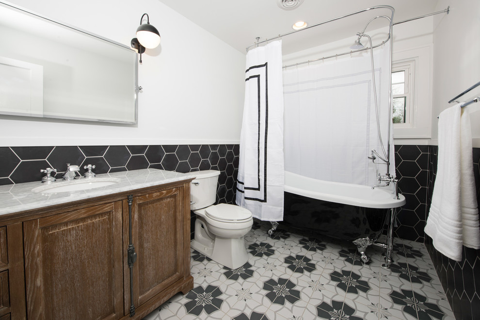 Inspiration for a bathroom in Indianapolis with furniture-like cabinets, light wood cabinets, a claw-foot tub, a one-piece toilet, black and white tile, ceramic tile, white walls, ceramic floors, a drop-in sink and marble benchtops.