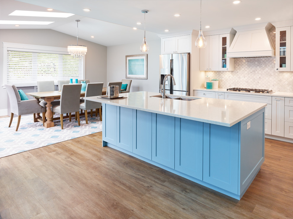 Photo of a beach style open plan kitchen in Vancouver with a drop-in sink, shaker cabinets, black cabinets, quartz benchtops, grey splashback, mosaic tile splashback, stainless steel appliances, vinyl floors, with island and white benchtop.