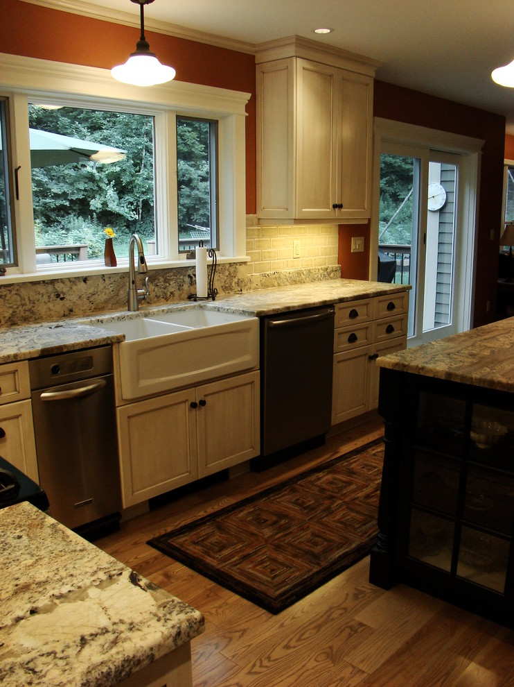 Large traditional l-shaped eat-in kitchen in Portland Maine with a farmhouse sink, recessed-panel cabinets, distressed cabinets, granite benchtops, multi-coloured splashback, porcelain splashback, stainless steel appliances, light hardwood floors and with island.