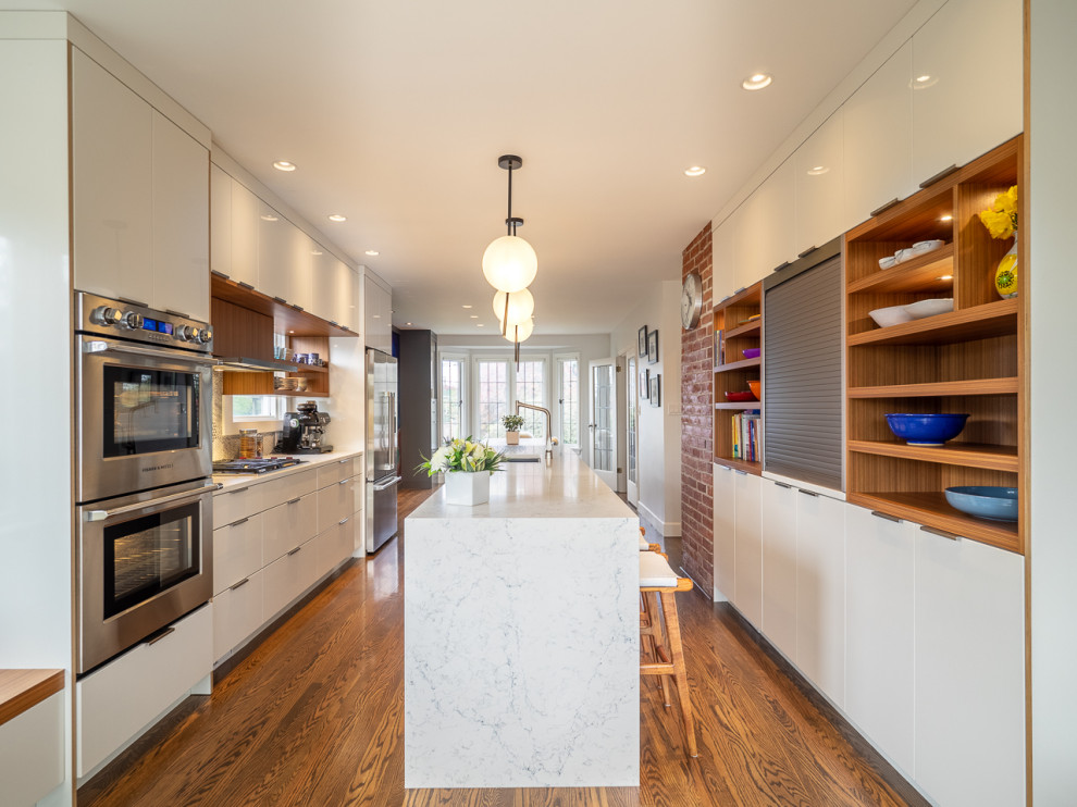 Design ideas for a mid-sized contemporary galley kitchen in Vancouver with an undermount sink, flat-panel cabinets, white cabinets, stainless steel appliances, dark hardwood floors, with island, brown floor and white benchtop.
