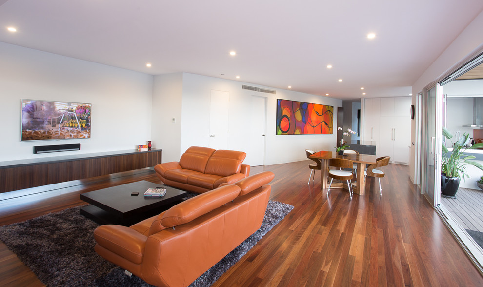 Contemporary living room in Melbourne with white walls, dark hardwood floors and no fireplace.