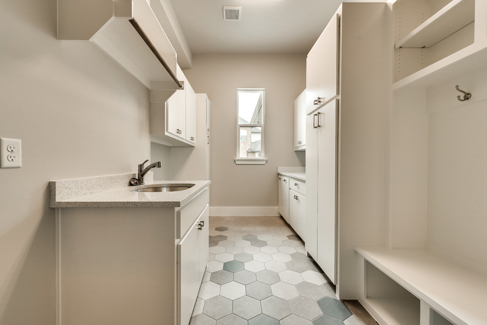 Photo of a large transitional galley dedicated laundry room in Dallas with an undermount sink, flat-panel cabinets, white cabinets, terrazzo benchtops, beige walls, ceramic floors, a side-by-side washer and dryer, multi-coloured floor and multi-coloured benchtop.