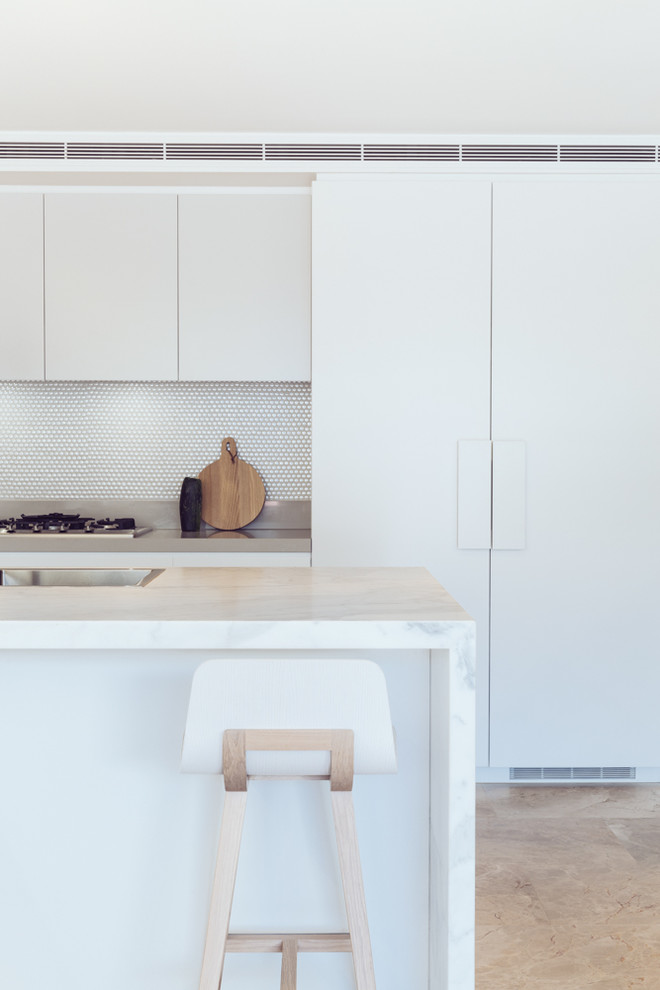 Design ideas for a small contemporary u-shaped eat-in kitchen in Sydney with an undermount sink, flat-panel cabinets, white cabinets, marble benchtops, white splashback, mosaic tile splashback, stainless steel appliances, limestone floors and with island.