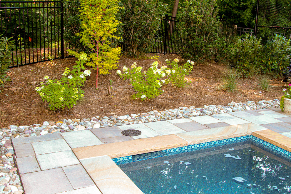 This is an example of a large arts and crafts side yard rectangular lap pool in Other with a pool house and natural stone pavers.