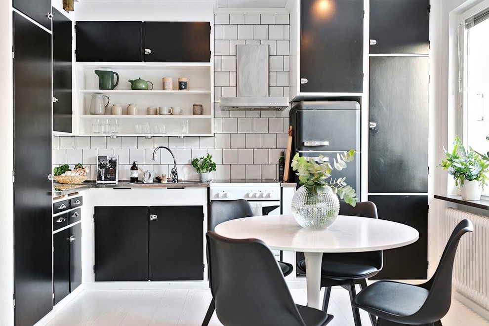 Inspiration for a mid-sized scandinavian l-shaped eat-in kitchen in Stockholm with a single-bowl sink, flat-panel cabinets, black cabinets, stainless steel benchtops, white splashback, coloured appliances, painted wood floors and no island.