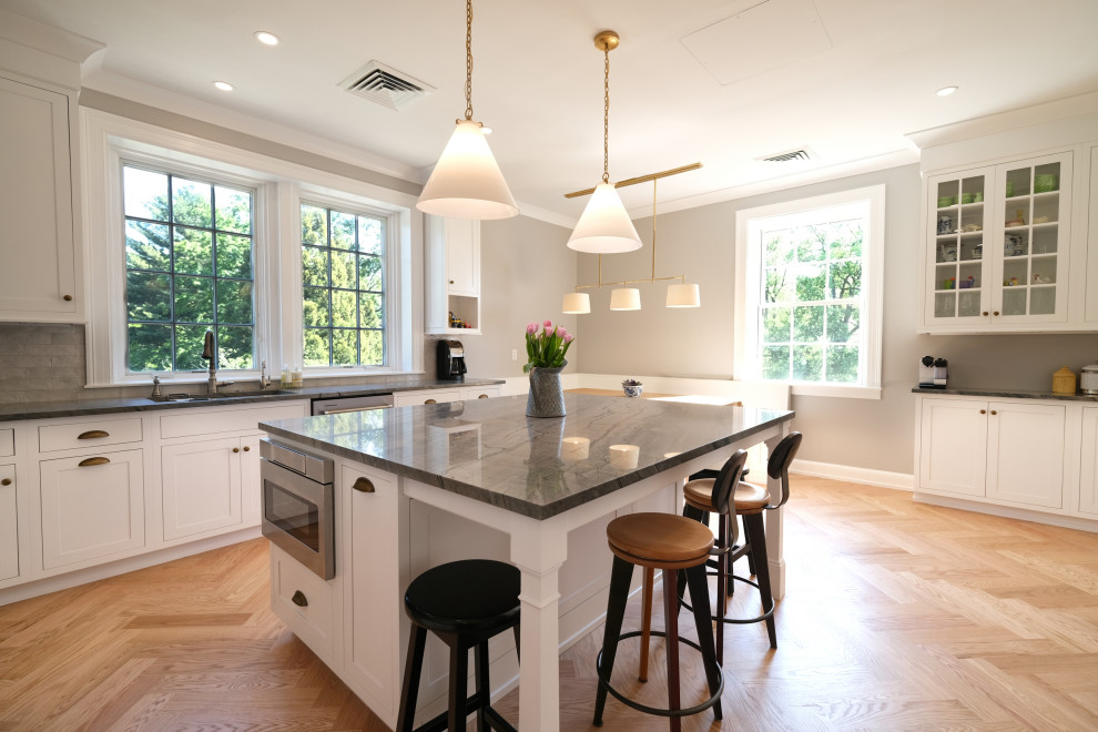 Design ideas for a large l-shaped eat-in kitchen in Baltimore with an undermount sink, beaded inset cabinets, white cabinets, marble benchtops, grey splashback, porcelain splashback, stainless steel appliances, light hardwood floors, with island, brown floor and blue benchtop.