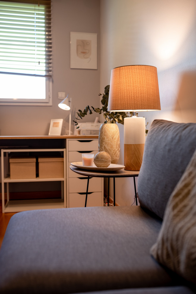 Bild på ett mellanstort minimalistiskt hemmabibliotek, med grå väggar, ljust trägolv och ett fristående skrivbord