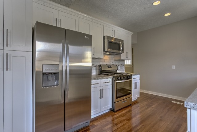 Small transitional galley medium tone wood floor eat-in kitchen photo in Omaha with an undermount sink, shaker cabinets, white cabinets, granite countertops, white backsplash, stone tile backsplash, stainless steel appliances and a peninsula