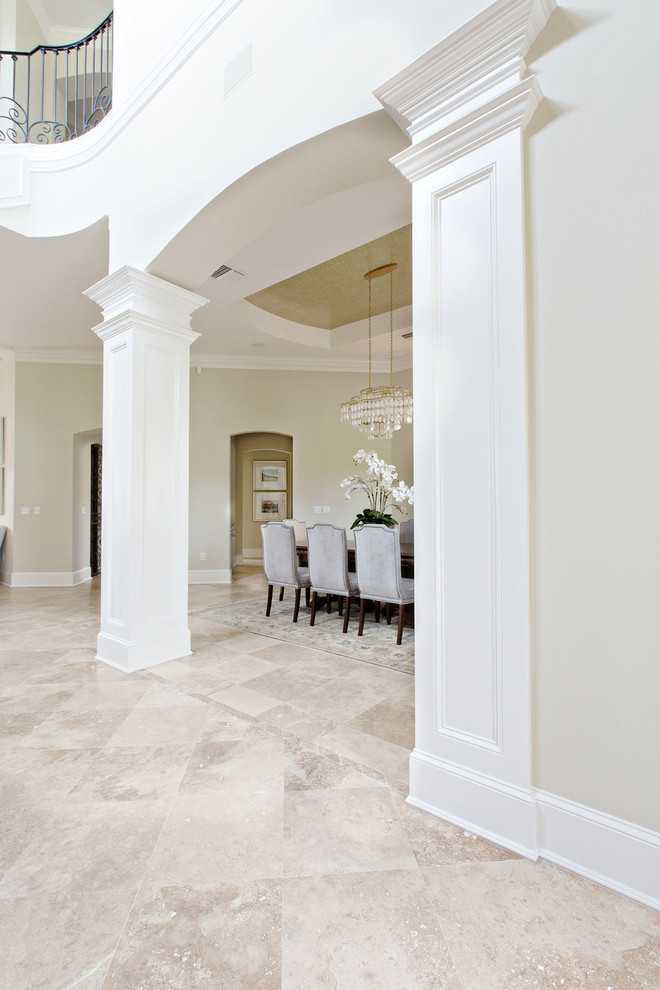 Photo of a large transitional entryway in Orange County with beige walls and travertine floors.