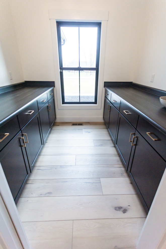 Mid-sized 1960s galley vinyl floor, beige floor and vaulted ceiling laundry closet photo in Cincinnati with beaded inset cabinets, dark wood cabinets, wood countertops and black countertops