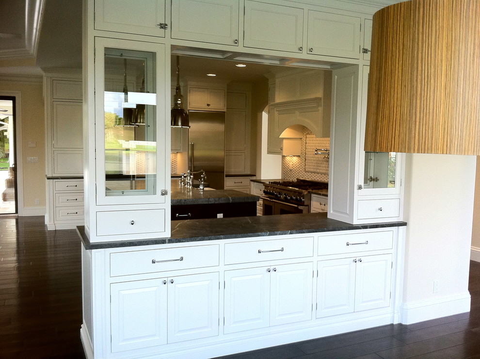 Inspiration for a large transitional u-shaped dark wood floor and brown floor open concept kitchen remodel in Miami with a farmhouse sink, shaker cabinets, white cabinets, granite countertops, multicolored backsplash, stone tile backsplash, stainless steel appliances and an island