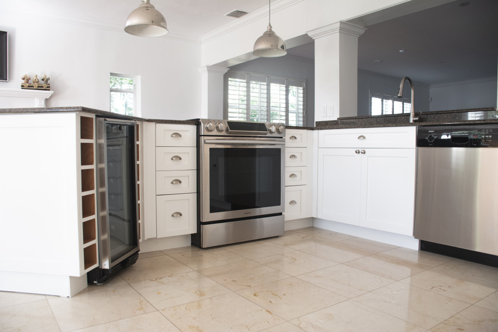 Inspiration for a mid-sized transitional eat-in kitchen remodel in Miami with a single-bowl sink, shaker cabinets, white cabinets, granite countertops, black backsplash, granite backsplash, stainless steel appliances, a peninsula and black countertops
